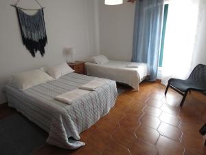 a bedroom with two beds and a chair and a window at Casas da praia Supertubos in Peniche