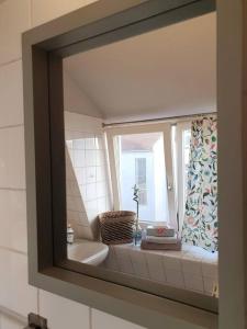 a mirror reflecting a bathroom with a sink and a window at Rostock hautnah erleben - schöne Maisonette 2OG in Rostock
