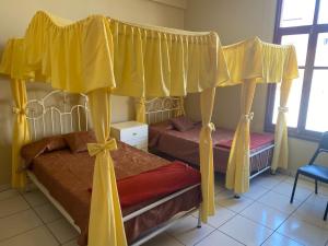 2 Betten mit gelben Vorhängen in einem Schlafzimmer in der Unterkunft Dpto Bolivar Hermoso, amplio y bien ubicado en la chura Tarija in Tarija