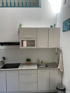 a white kitchen with a sink and a microwave at Le GreenStairs - Ranch du Laubenrain in Jungholtz
