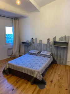 een slaapkamer met een bed in een kamer met houten vloeren bij La Maison Rose in Caromb +4 foto's