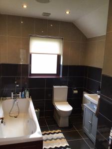 baño con bañera, aseo y ventana en Errew Lodge, en Mohill