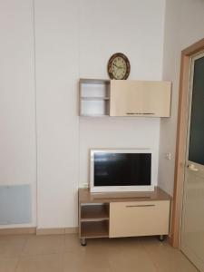 uma televisão numa bancada com um relógio na parede em Apartment Emma em Velipojë