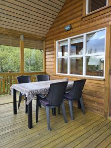 uma mesa e cadeiras no deque de uma cabina em Cozy Cottage in Icelandic nature with Hot tub em Akranes