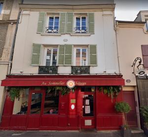 a red storefront of a building with green shutters at A modern flat in the center of Fontainebleau in Fontainebleau