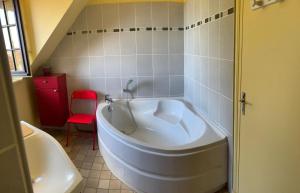 a large white tub in a bathroom with a red chair at Chambre d'hote chez Maud in Saint-Sauveur-Marville