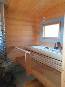 Holzhütte mit einem Bett und einem Fenster in der Unterkunft Stunning log cabin 45m2 on the shore of Kallavesi. in Kuopio