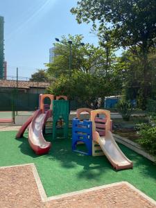 um parque infantil com diferentes escorregas coloridos na relva em Cond. Mediterrâneo Flat no Rio de Janeiro
