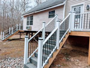 a house with white railings and a porch with a staircase at Our Private Wooded Cabin in Chatham