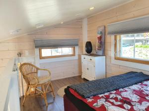クオピオにあるStunning log cabin 45m2 on the shore of Kallavesi.のベッドと椅子が備わる小さな家の中のベッドルーム1室です。