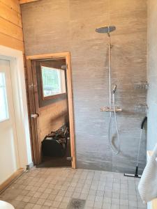 baño con ducha y puerta de cristal en Stunning log cabin 45m2 on the shore of Kallavesi., en Kuopio