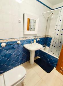 a blue tiled bathroom with a sink and a toilet at Casa Cris in La Lajita