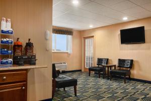a waiting room with chairs and a flat screen tv at FairBridge Inn Express Buffalo Airport Williamsville in Williamsville