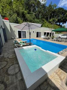 einen Pool mit Sonnenschirm neben einem Haus in der Unterkunft Villa Flor 2022 in Los Plátanos