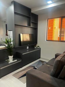 Lindo apartamento في كوريتيبا: غرفة معيشة مع أريكة وتلفزيون بشاشة مسطحة
