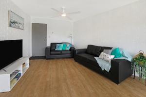 a living room with a black couch and a flat screen tv at CANAL7-ON THE MOOLOOLABA CANAL! in Mooloolaba