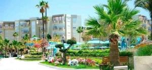 a park with palm trees in front of a building at PALM LAKE RESORT FOLLA in Monastir