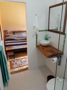 uma casa de banho com um lavatório, um espelho e uma cama em Recanto do Ipê em Extrema