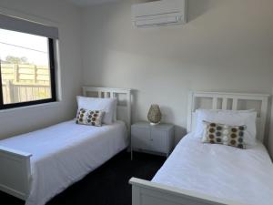 two white beds in a room with a window at Luxury on Bayview Wifi Linen included in Inverloch