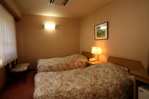 una camera d'albergo con due letti e un telefono di Shibu Hotel a Yamanouchi