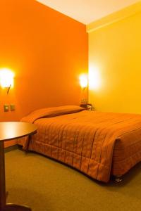1 dormitorio con 1 cama grande y paredes de color naranja en Mosoq Inn en Puno