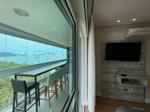 a room with a balcony with a flat screen tv at TR01- Suíte+1 | Vista Incrível | Piscina|Big Wheel in Balneário Camboriú