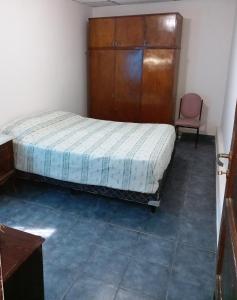 a bedroom with a bed and a wooden cabinet and a chair at SUMAQ WASICHA SALTA in Salta