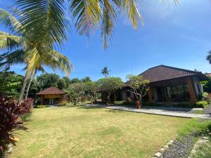 una casa con un patio y una palmera en Badini Homestay Pemuteran Bali, en Pemuteran