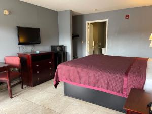 a bedroom with a bed and a tv and a desk at Majestic Inn in Longview