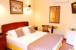 Un dormitorio con una cama, una mesa y un espejo. en Hotel Americano, en Arica
