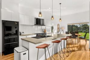 a kitchen with white cabinets and a island with bar stools at Castlebay in Wimbledon Heights