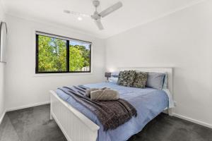 a white bedroom with a bed with a window at Castlebay in Wimbledon Heights