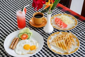 een tafel met borden ontbijtproducten en een kopje koffie bij The Gria Unique Ubud in Ubud