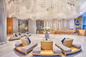 a lobby with chairs and a large chandelier at Vasa Hotel Surabaya in Surabaya