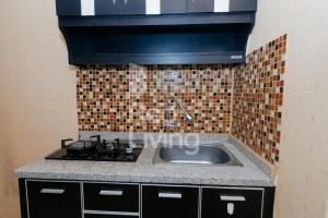 a kitchen with a sink and a tile wall at RedLiving Apartemen Bassura City - Aokla Property Tower Dahlia in Jakarta
