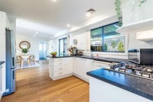 a kitchen with white cabinets and a large window at Akoya House 122 Tomaree Rd Pet friendly linen air conditioning WiFi and boat parking in Shoal Bay