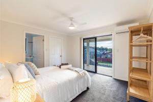 1 dormitorio con cama blanca y balcón en Akoya House 122 Tomaree Rd Pet friendly linen air conditioning WiFi and boat parking, en Shoal Bay