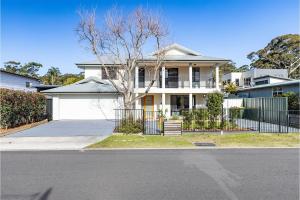 a white house with a fence in front of it at Akoya House 122 Tomaree Rd Pet friendly linen air conditioning WiFi and boat parking in Shoal Bay