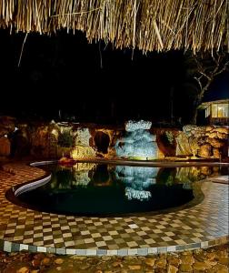 a swimming pool in a resort at night at Pugmarks Jungle Lodge in Chekadi