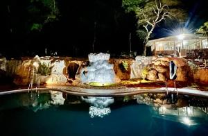 una fuente en medio de una piscina por la noche en Pugmarks Jungle Lodge en Chekadi
