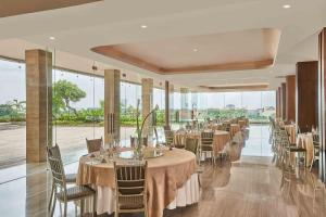 泗水的住宿－泗水瓦薩酒店，用餐室配有桌椅和大窗户