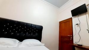 a bedroom with a bed with a black headboard at Homestay Merpati Dieng Syariah RedPartner in Diyeng