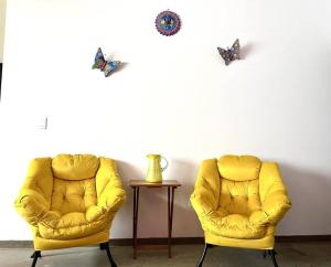 two yellow chairs and a table with butterflies on the wall at Apartment in the touristic heart of Mexico City in Mexico City
