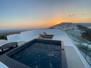 a hot tub on the roof of a house with the sunset at ArmonOia Suites in Oia