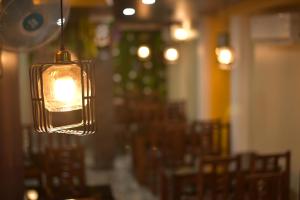 un appareil lumineux suspendu dans un restaurant avec des chaises dans l'établissement Hotel Maa International, à Alīpur Duār
