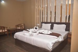 a bedroom with a bed with white towels on it at Hotel Maa International in Alīpur Duār