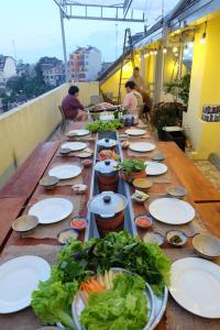 una larga mesa de madera con platos de comida. en Century House en Dalat