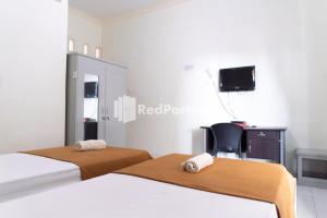 Kedaton的住宿－Wisma Aini Syariah Mitra RedDoorz，配有两张床铺、一张桌子和一台电视机的客房