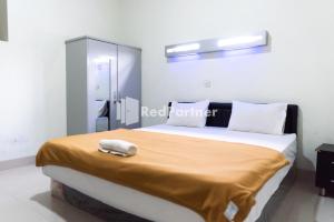 a bedroom with a bed with a phone on it at Wisma Aini Syariah Lampung Mitra RedDoorz in Kedaton