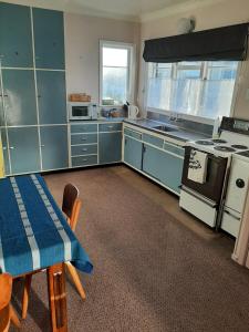 a kitchen with blue cabinets and a table with a blue tablecloth at Mary's Place in Opotiki